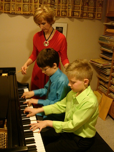 Jacqueline coaching two young boys in a piano duet